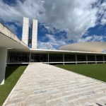 Vista externa do Congresso Nacional, em Brasília, com suas cúpulas e torres sob céu claro.