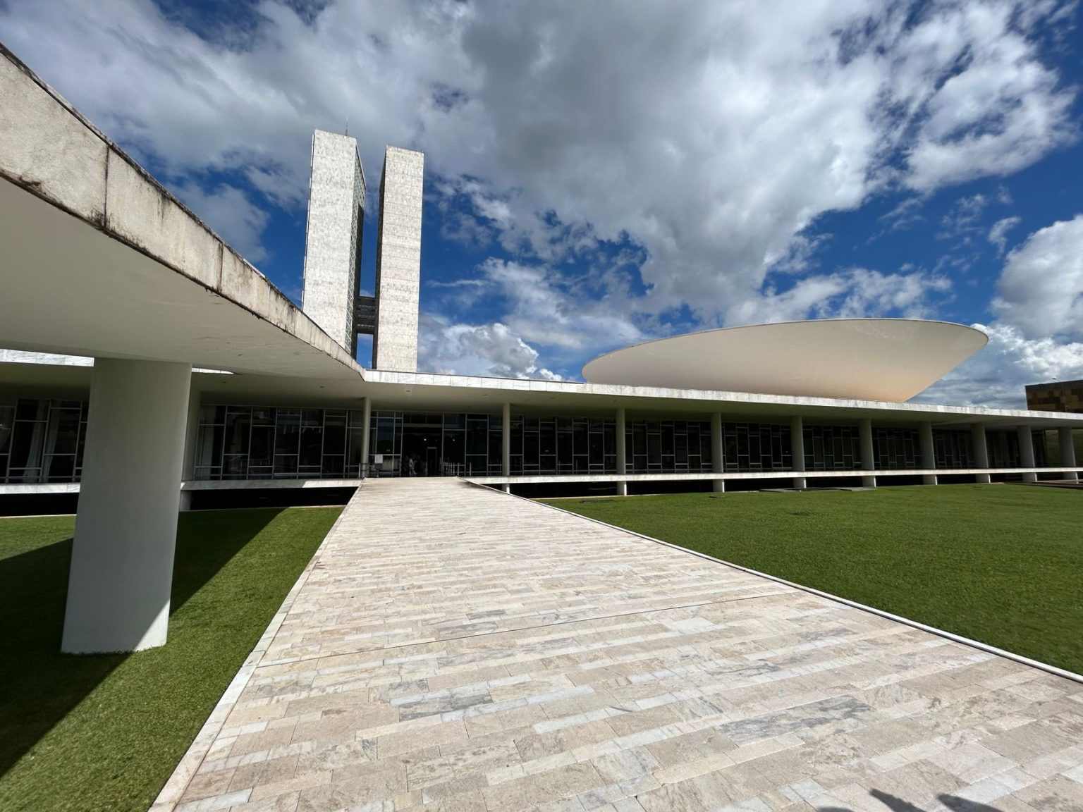 Vista externa do Congresso Nacional, em Brasília, com suas cúpulas e torres sob céu claro.