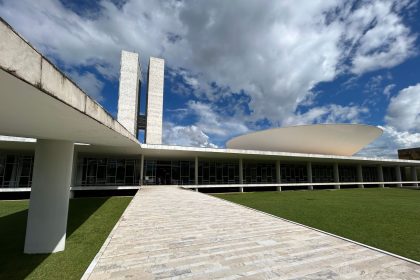 Vista externa do Congresso Nacional, em Brasília, com suas cúpulas e torres sob céu claro.